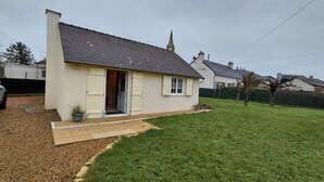 A small, single-story house with a sloped roof, a front door, and a small porch. - Small house located in a village 15min from Langeais (Hommes)