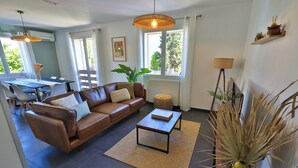Ein modernes Wohnzimmer mit einer braunen Ledersofa, einem Holztisch und einem großen Fenster, das für natürliches Licht sorgt.