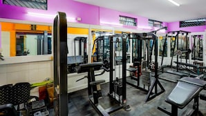 A gym with various exercise equipment, a bench, and a mirrored wall. - Deluxe Olive Star (Mysore)