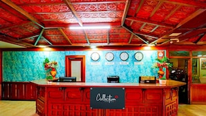 A reception desk with a sign reading "Collection" and clocks indicating different cities. - Deluxe Olive Star (Mysore)