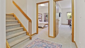 Eine Treppe mit hölzernen Geländern führt zu einem Schlafzimmer mit Bett und Fenster.