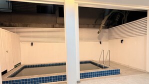 A spacious indoor pool area with tiled flooring, a central column, and a sloped ceiling. - Velora Jomtien Residence (Pattaya)
