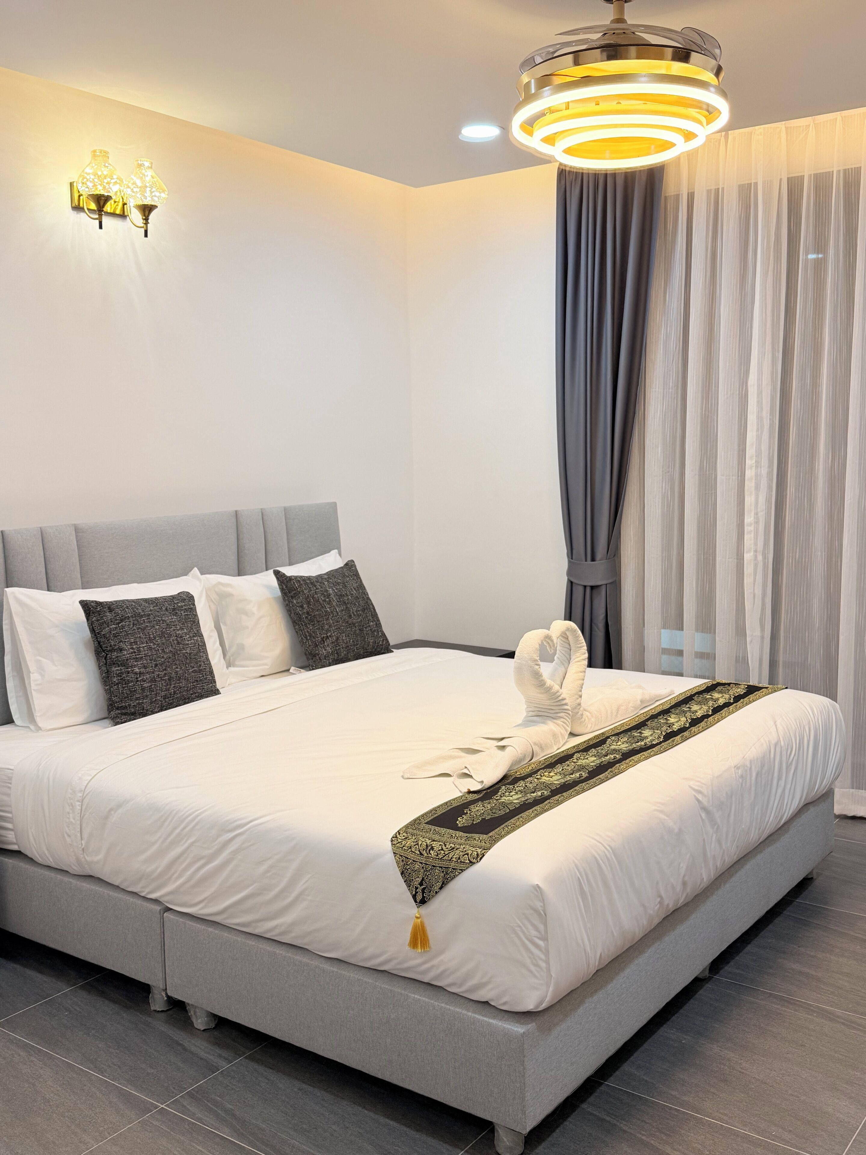 Une chambre d’hôtel moderne avec un grand lit, une serviette décorative et un luminaire original.