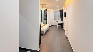 A modern hotel room with a bed, a small table, and a chair. - Velora Jomtien Residence (Pattaya)