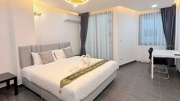 A modern hotel room with a large bed, a desk, and a chair. - Velora Jomtien Residence (Pattaya)