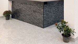 A reception area with a marble counter, a clock, and potted plants. - Velora Jomtien Residence (Pattaya)