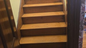A wooden staircase with a handrail and a floral-patterned curtain. - Keepsake Inn - Where Memories are Made (Colebrook)
