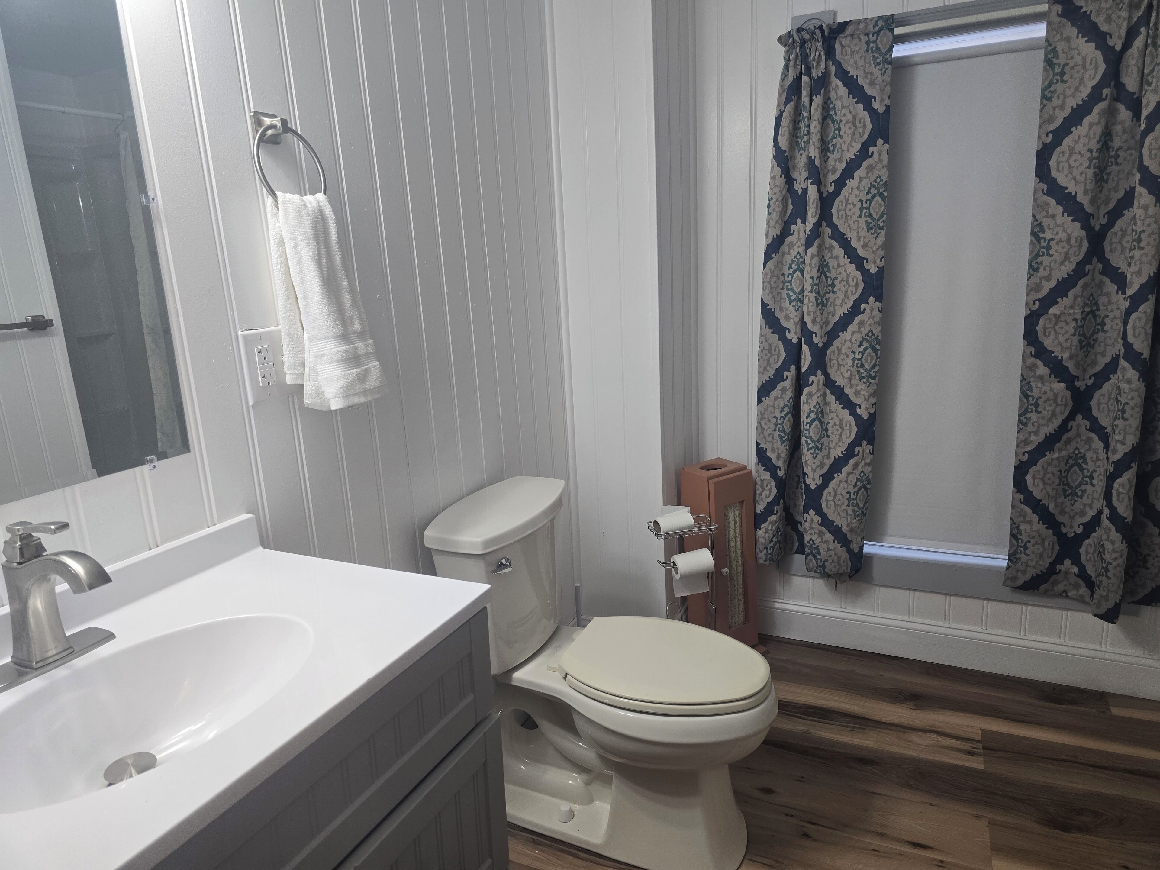 A bathroom with a white sink, toilet, and a shower curtain with a geometric pattern.