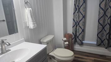A bathroom with a white sink, toilet, and a shower curtain with a geometric pattern.