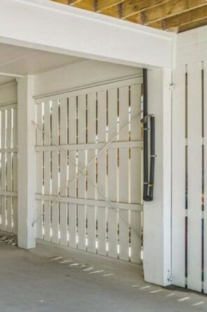 A parking garage with white metal gates and a concrete floor. - Newer Luxury 4-bedroom 4-bath cottage with community pool 2 minute walk to beach (Gulf Shores)