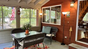A cozy room with a glass table, wicker chairs, and a colorful rug. - Lovely Maine Lakeside Cottage and Bunkhouse (Newfield)