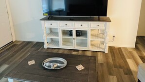 A room with a TV mounted on a white cabinet, a wooden floor, and a small table with a metal tray.