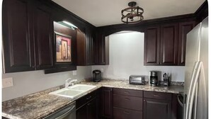 A kitchen with dark wood cabinets, a granite countertop, stainless steel appliances, and a built-in oven. - Waterfront River House on Brices Creek, New Bern (New Bern)