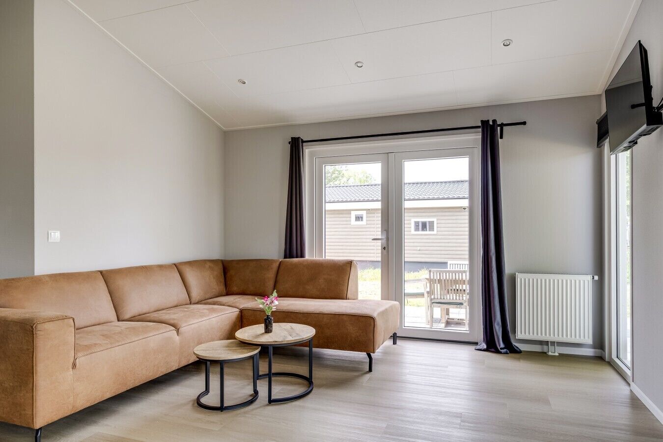 Una sala moderna con un sofá modular, una mesita redonda y vistas al exterior a través de un ventanal corredero.