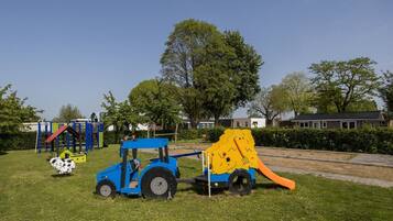 Une aire de jeux avec un tracteur bleu et une structure de jeu représentant un lion jaune.