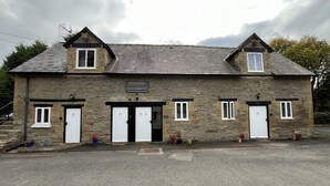 A stone building with six numbered doors, a sign indicating parking for customers only, and a gravel driveway. - The Bateman Arms (Shobdon)