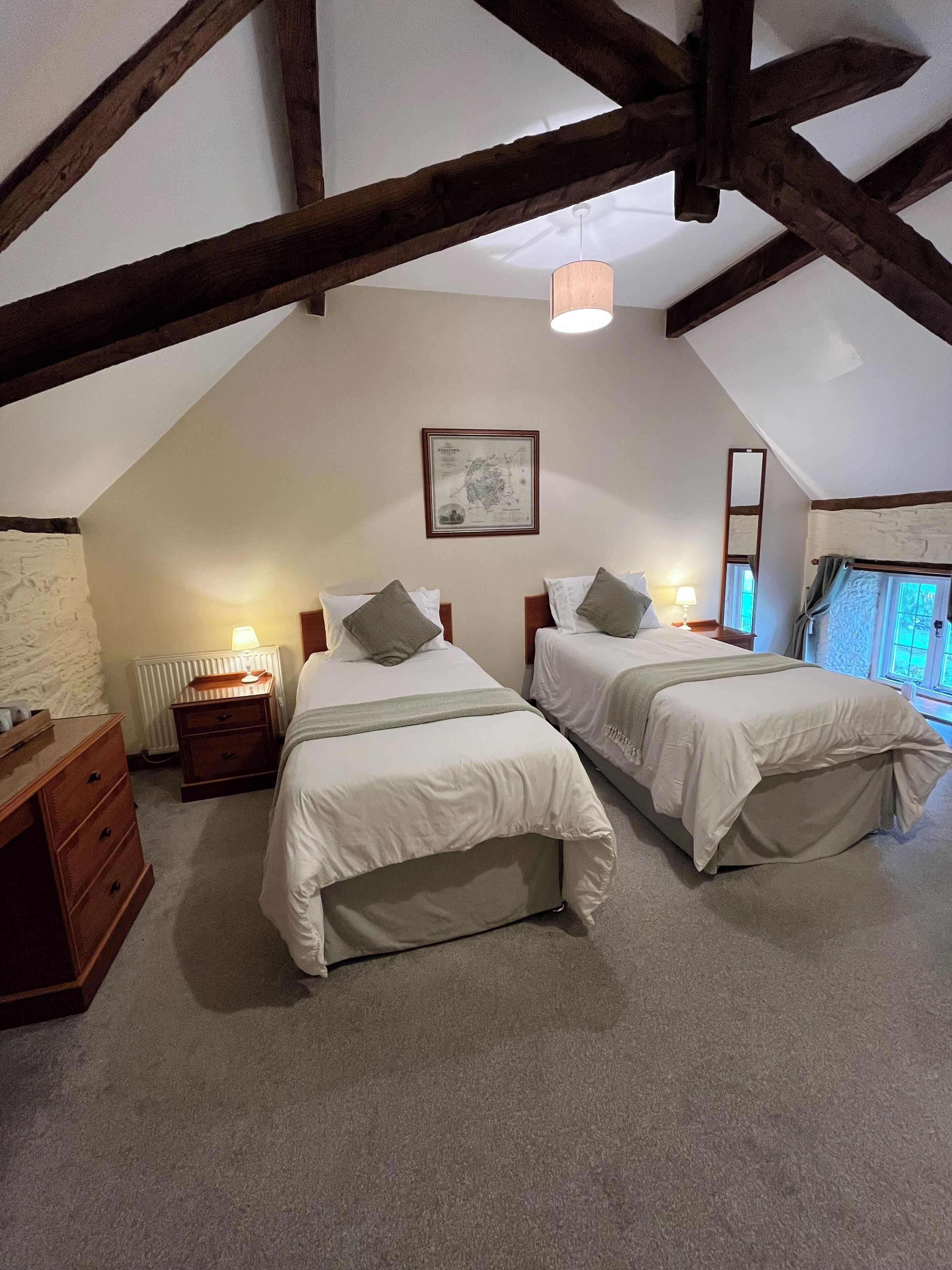 Ein Schlafzimmer mit zwei Betten, einer Holzkommode, einem Heizkörper und einer gerahmten Karte an der Wand.
