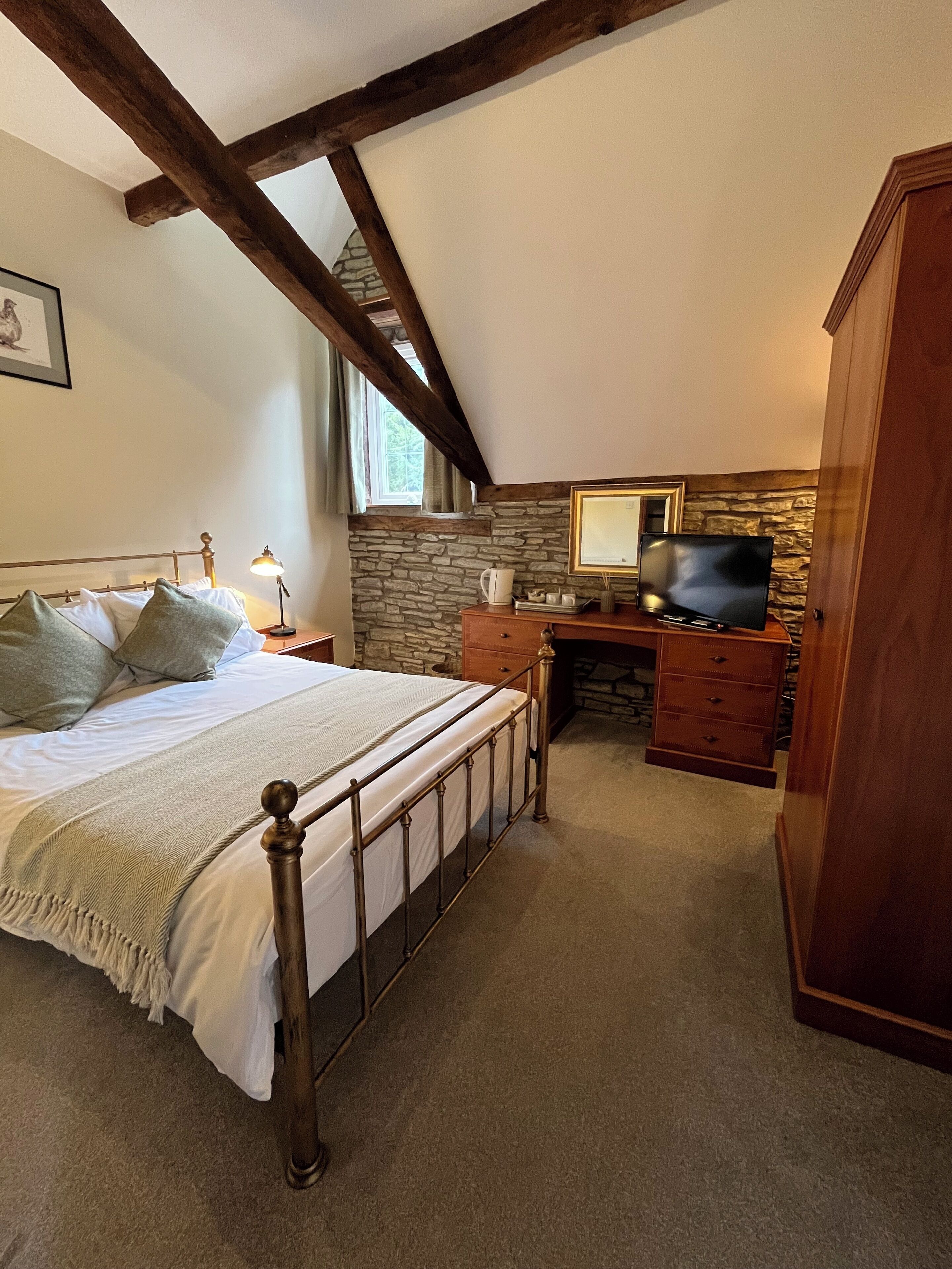 Ein Schlafzimmer mit einem Bett, einem Schminktisch, einem Fernseher und einer Steinwand.
