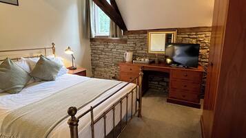 A bedroom with a bed, a dresser, a television, and a stone wall.