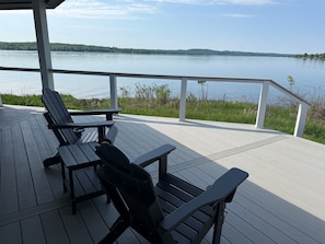 Une terrasse en bois, avec des chaises et une table, donnant sur un lac paisible.