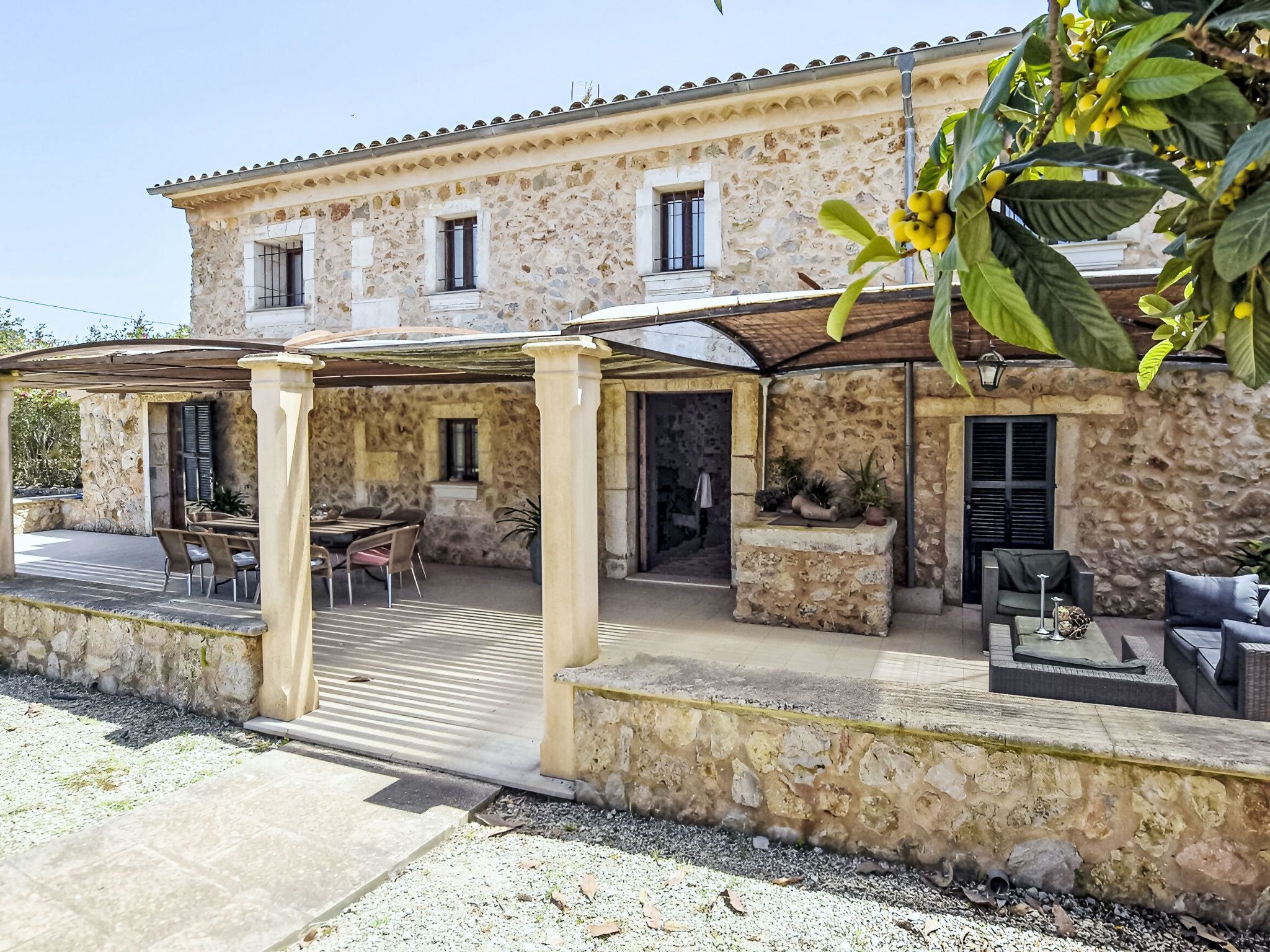A stone building with a covered patio, outdoor seating, and a garden area.