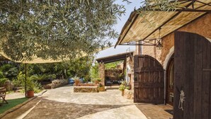 A courtyard with a stone pathway, potted plants, outdoor furniture, and a rustic building with a wooden door. - MONTSERRAT  ( SON PERETO ) by Interhome (Manacor)