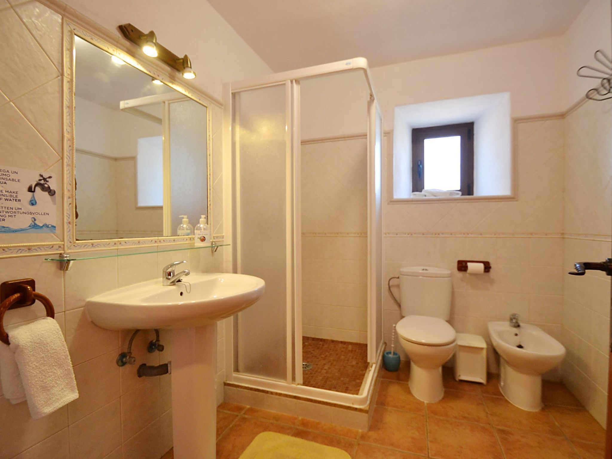 Une salle de bain équipée d’un lavabo, d’un miroir, de toilettes, d’un bidet et d’une cabine de douche.