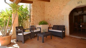 An outdoor patio with wicker furniture, a potted plant, and a stone wall. - Xim vell by Interhome (Felanitx)