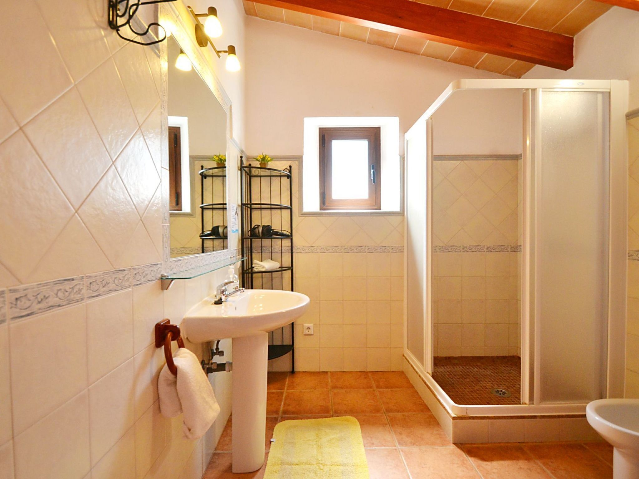 A bathroom with a sink, mirror, towel rack, and a glass-enclosed shower.