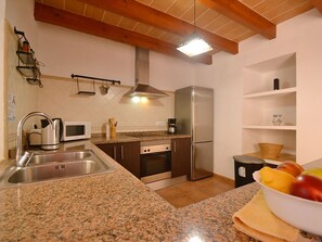 A kitchen with granite countertops, stainless steel appliances, a microwave, a coffee maker, and a fruit bowl. - Xim vell by Interhome (Felanitx)