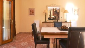 Un espace repas avec un sol en marbre, une table en bois, des chaises noires et deux lampes.