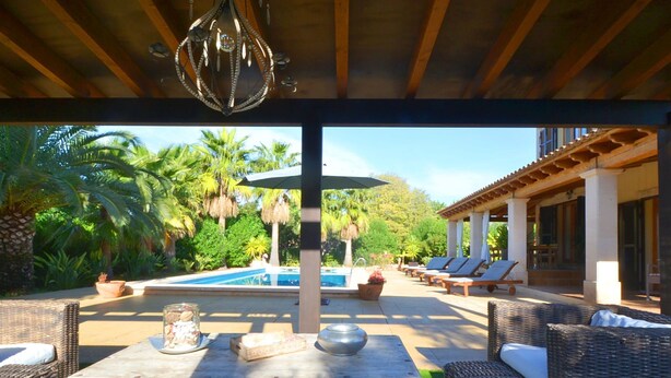 Un espace extérieur avec une piscine, des chaises longues et une table agrémentée d’un vase décoratif et d’un bocal en verre.