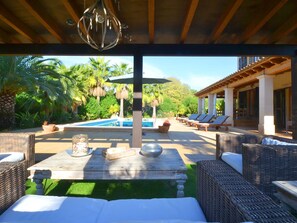 An outdoor pool area with lounge chairs and a table with a decorative bowl and a glass jar. - Wunderschön restauriertes Landhaus by Interhome (Son Sardina)