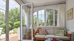 Una sala de estar acogedora con un sofá, una mesa de centro y un ventanal corredero que da a un jardín.