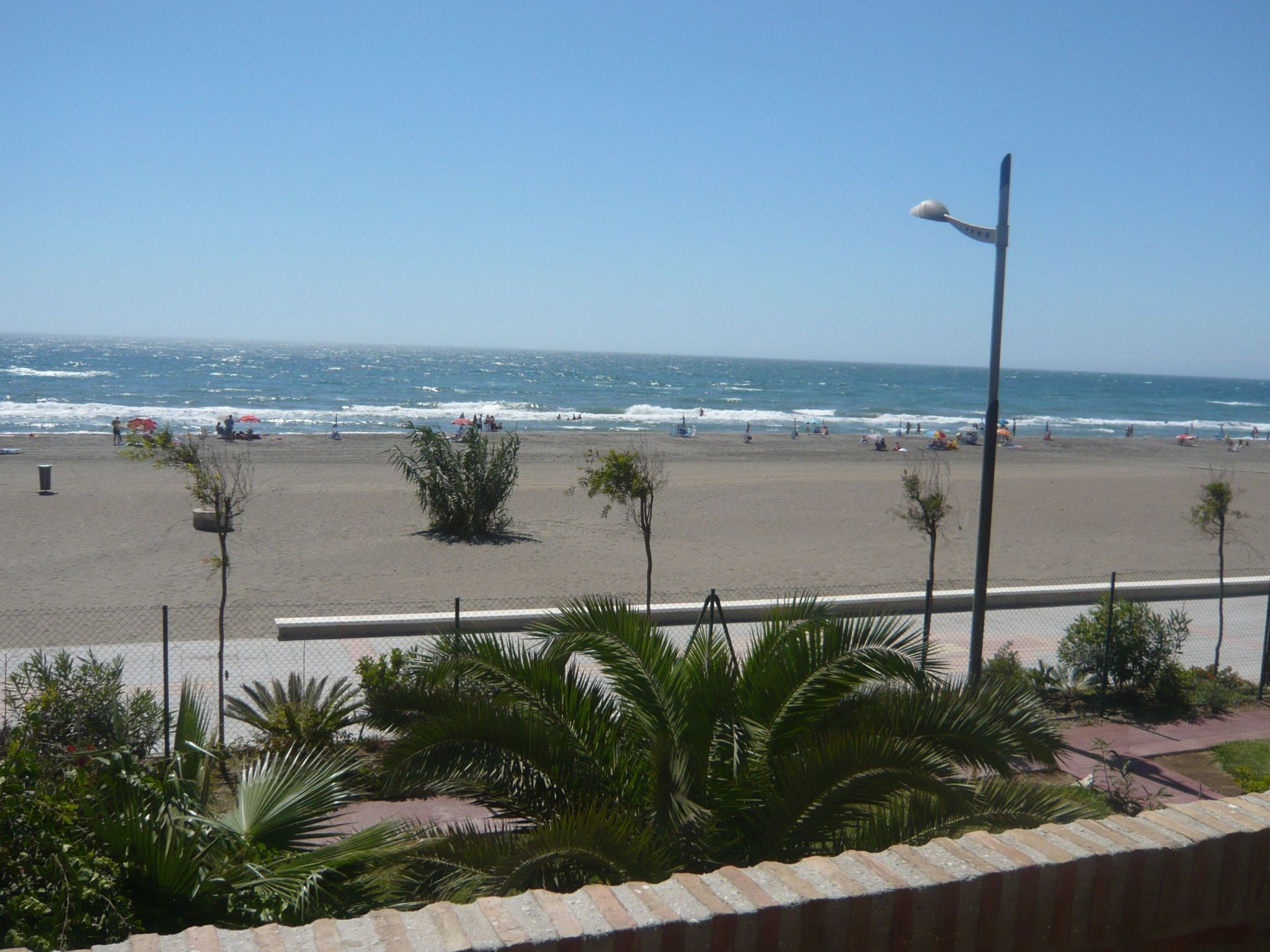 Una playa con valla, palmeras y farol.