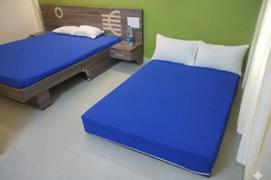 Zwei Einzelbetten mit blauer Bettwäsche in einem Zimmer mit grünen Wänden und einem Holzkopfstück.