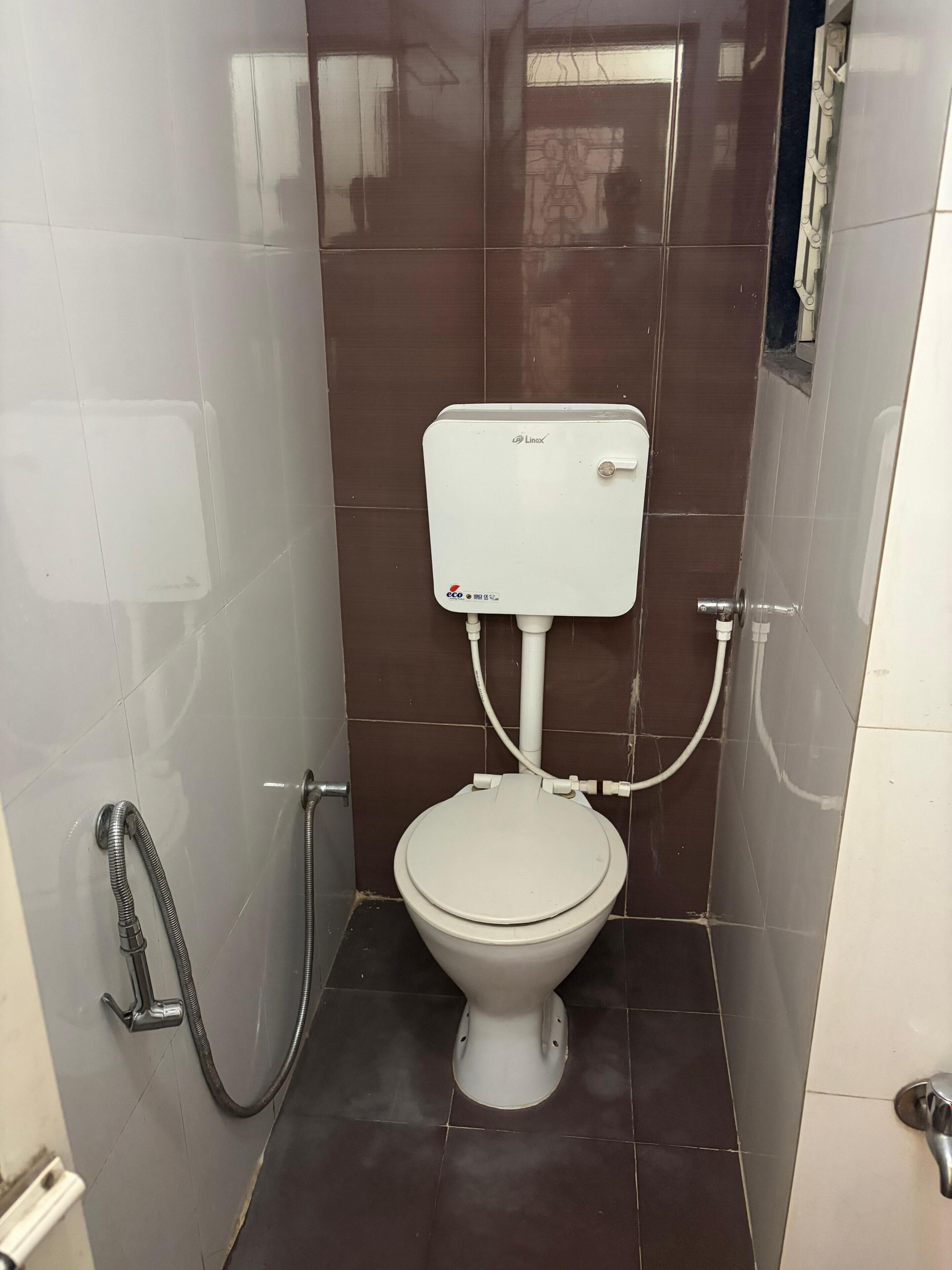 Un baño pequeño con inodoro blanco, ducha y lavamanos empotrado.
