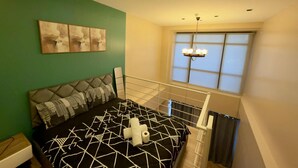 A bedroom with a bed, a green wall, a window with curtains, and a ceiling light. - Makati City Poblacion 1 bedroom  (Makati)