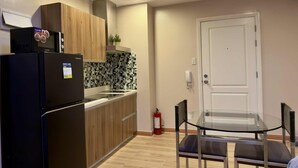 A compact kitchen with a refrigerator, microwave, and a tiled backsplash. - Makati City Poblacion 1 bedroom  (Makati)