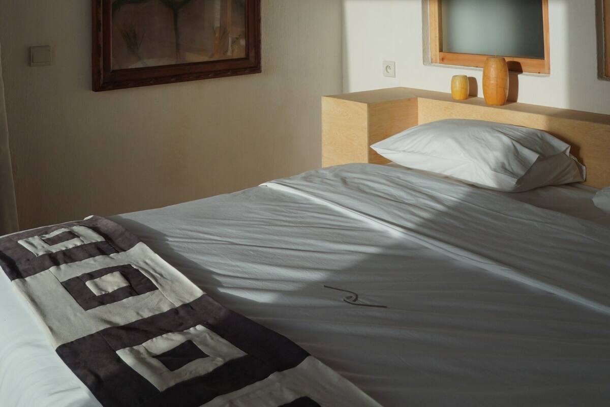 Un dormitorio con cama, un cuadro enmarco, un cabecero de madera y un espejo.