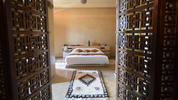 Un dormitorio con cama, mesitas de noche, una pared decorativa y una alfombra estampada.
