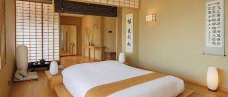 A hotel room with a bed, a bedside table, a lamp, and a wall with a sign.