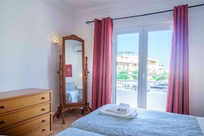 A hotel room with a bed, a wooden dresser, a mirror, and a view of the outside. - One-bedroom apartment at Hotel Solar do Sol (Albufeira)