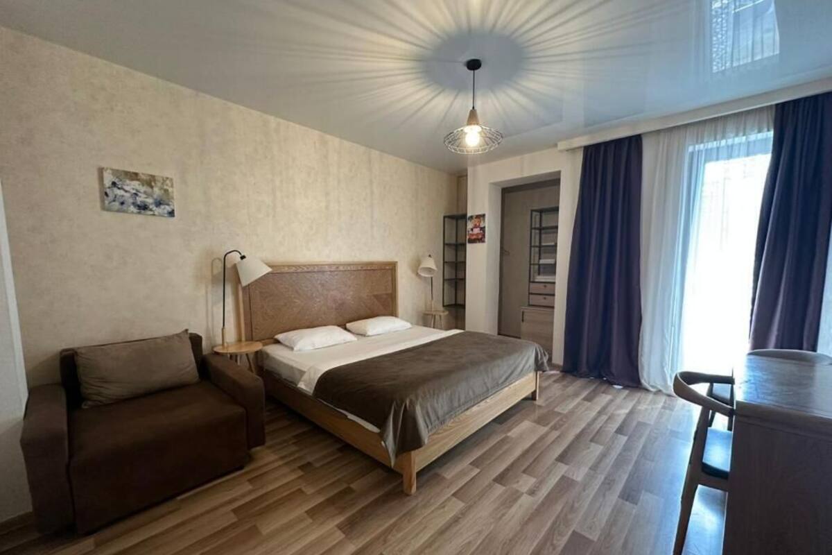 A bedroom with a bed, a sofa, a desk, and a chair.