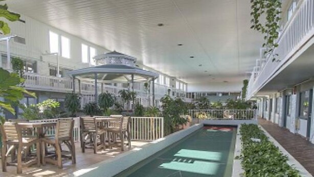 Un espace piscine intérieur comprenant une table de jeu de palet, des sièges et des plantes en pot.
