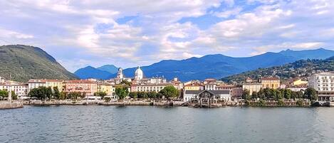 A waterfront cityscape with historic buildings, a prominent dome, and mountains in the background.