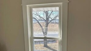 A window with a view of a tree and a paved area outside. - Wine Trail and Sunset Vibes in this Welcoming 3-bedroom home in Cayuga! (Cayuga)