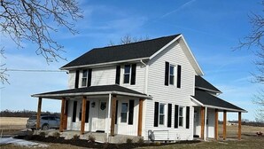 A two-story house with a porch, a garage, and a driveway. - Wine Trail and Sunset Vibes in this Welcoming 3-bedroom home in Cayuga! (Cayuga)