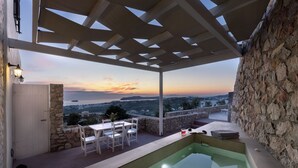 Ένας σκεπαστός εξωτερικός χώρος με πισίνα, πέτρινα τοιχώματα και θέα στο τοπίο.