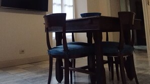 En matplats med en kristallkrona, en platt-TV och ett fönster med randiga gardiner.